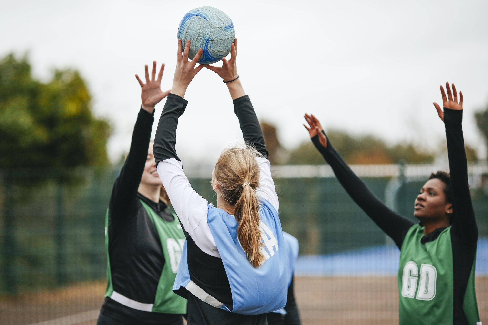 Female netball teams throwing ball on netball court